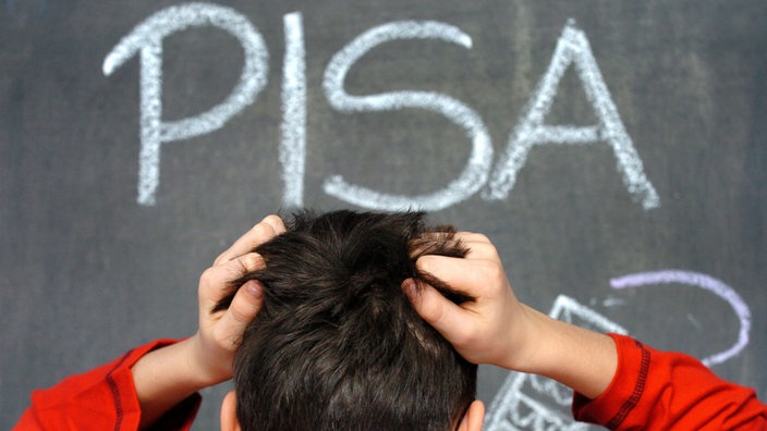 Ein Schüler rauft sich die Haare vor einer Tafel mit der Ausschrift "Pisa"
