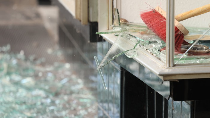 In Oberhausen räumen Menschen Glas aus ihrem durch eine Explosion beschädigtes Geschäft aus. Auch das Parteibüro der Linke war 2022 betroffen