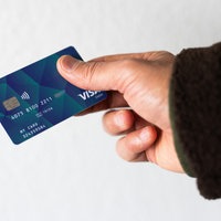 Ein Geflüchteter hält eine Debitkarte in der Hand