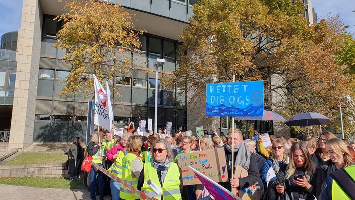 Menschen halten bunte Plakate bei einer Demonstration vor dem Düsseldorfer Landtag