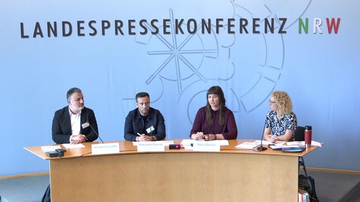 Mira Berlin, Mohamed Kouras und Menderes Candan sitzen an einem Rednertisch einer Pressekonferenz im NRW-Landtag
