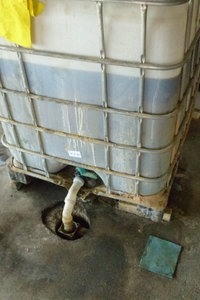Ein weißer Kanister mit Giftmüll aus der Drogenproduktion leitet mit einem Rohr flüssige Chemikalien in die Erde