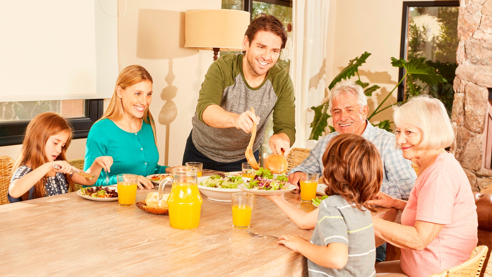 Erweiterte Familie mit Großeltern und Kindern beim Mittagessen am Esstisch