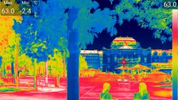 Aufnahme einer Wärmebildkamera:  Zwei Menschen sitzen im Schatten von Bäumen