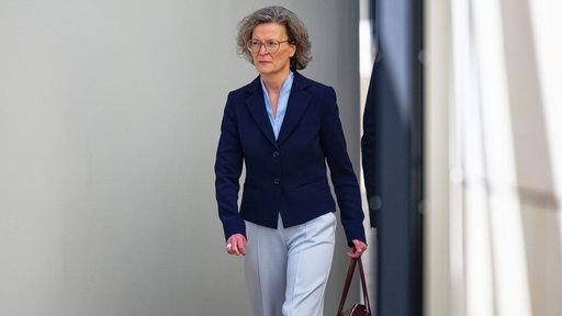 Ina Scharrenbach geht mit einer Handtasche in der Hand durch den Landtag NRW