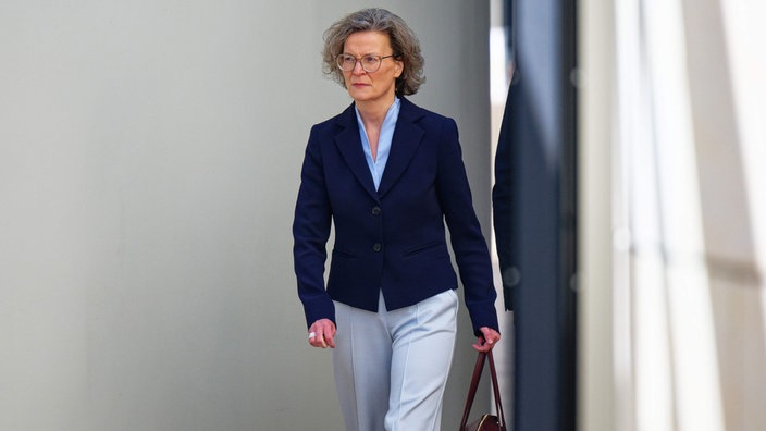 Ina Scharrenbach geht mit einer Handtasche in der Hand durch den Landtag NRW