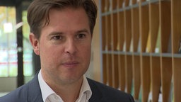  Tobias Hentze vom Institut der Deutschen Wirtschaft vor einer Regalwand.