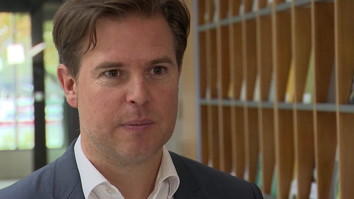  Tobias Hentze vom Institut der Deutschen Wirtschaft vor einer Regalwand.