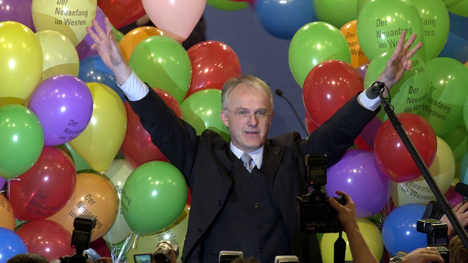 Jürgen Rüttgers hebt die Arme, steht inmitten bunter Luftballons, Aufnahme aus dem Jahr 2000