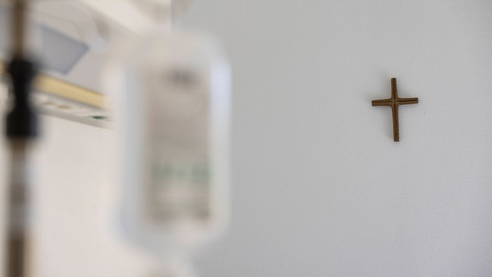  Ein Krankenzimmer im Katholischen Krankenhaus KKH in Erfurt. Ein Kreuz hängt an der weißen Wand und im Vordergrund verschwommen Krankenhaus Einrichtung.