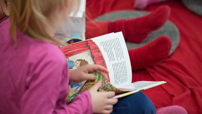 Ein Kind hält ein Buch mit Text und Bildern in der Hand