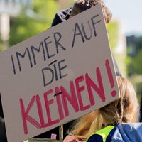 Zwei Kinder sind vor dem NRW-Landtagsgebäude teil einer Demonstration und halten Schilder hoch.