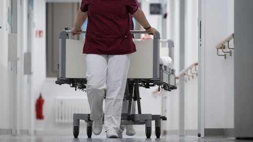 Krankenpflegerin schiebt ein Krankenbett in einem Krankenhaus durch den Gang