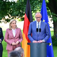 Friedrich Merz steht an einem Rednerpult, neben ihm Nina Warken, Caresten Linnemann und Philipp Amthor. Hinter ihnen die deutsche und die europäische Flagge.