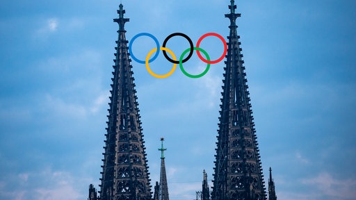 Bildmontage von den Spitzen des Kölner Doms zwischen denen die olympischen Ringe platziert sind