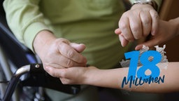 Eine Pflegekraft hält die Hände einer zu Pflegenden und hilft ihr beim Aufstehen