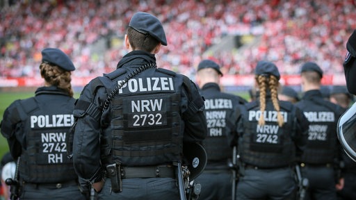 Mehrere Polizeibeamte der Polizei NRW stehen im Fußballstadion