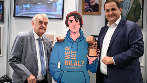 Herbert Reul und Nathanael Limisnki (beide CDU) mit der Videospielfigur "Bilal"