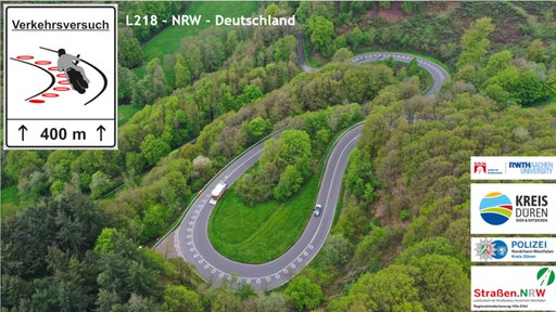 Fahrbahnmarkierungen auf einer kurvigen Straße aus der Vogelperspektive.