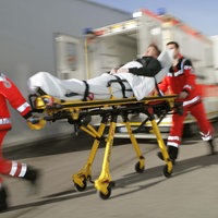 Zwei Sanitäter ziehen eine Trage mit einem Patienten drauf.