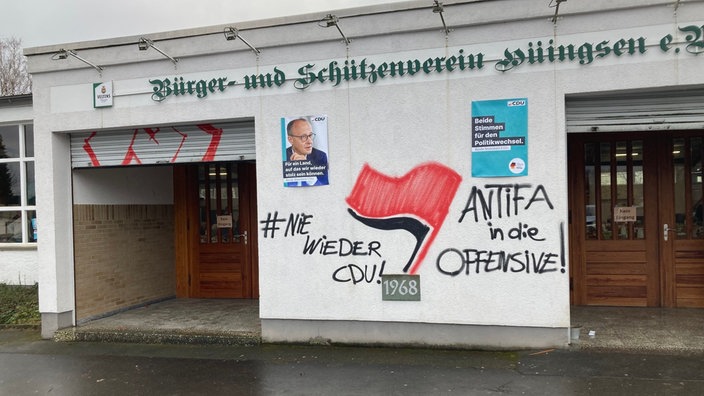 Schmiererei unter Merz-Plakat