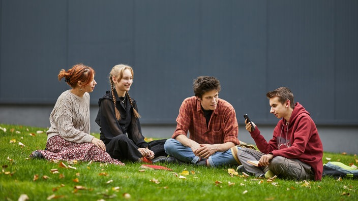 Studierende sitzen auf Wiese