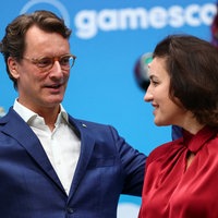 Wüst und Baer unterhalten sich auf der Gamescom, im Hintergrund sind Cosplayer zu sehen