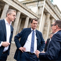 Stefan Evers, Hendrik Wüst und Mario Röllig im Gespräch miteinander vor dem Brandenburger Tor.