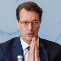 Ministerpräsident Hendrik Wüst spricht mit konzentriertem Blick in ein Mikrofon, die Hände vor dem Körper zusammengelegt.