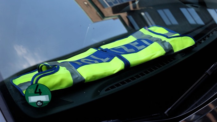 Eine Polizeiweste liegt auf der Amatur eines Polizeiwagens