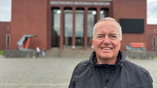 Ein Mann mit grauen Haaren lächelt in die Kamera.