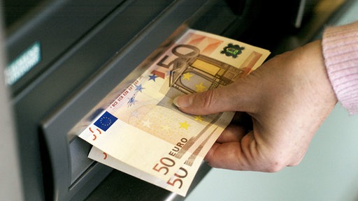 Hand mit Geldscheinen am Automaten