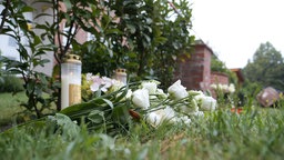 Blumen und Kerzen liegen und stehen vor dem Gebäude einer Jugendeinrichtung. In der Einrichtung waren mehrere Menschen durch Schüsse gestorben.