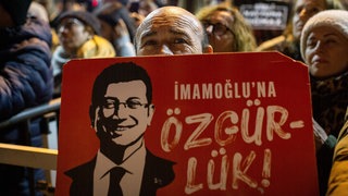 Bürger halten Ekrem Imamoglu-Plakate hoch.