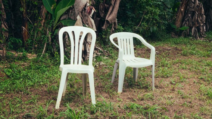 Cover "DeBÍ TíRAR MáS FOToS" von Bad bunny - zwei Ploastikstühle in einem tropischen Garten
