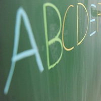 Ein Mädchen schreibt das ABC auf eine Schultafel