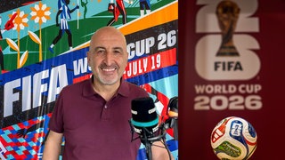 Tuncay Özdamar im WDR Cosmo Studio mit FIFA Worldcup 2026 Plakat im Hintergrund