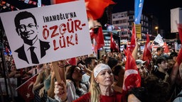 Eine Frau hält ein Plakat mit der Aufschrift „Freiheit für Ekrem Imamoglu“. 