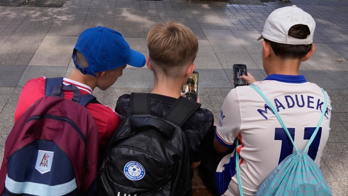 Hugo W., Hardy M. i Edan A., svi 11 godina stari, koriste svoje smartfone u dvorištu škole u Sidneju