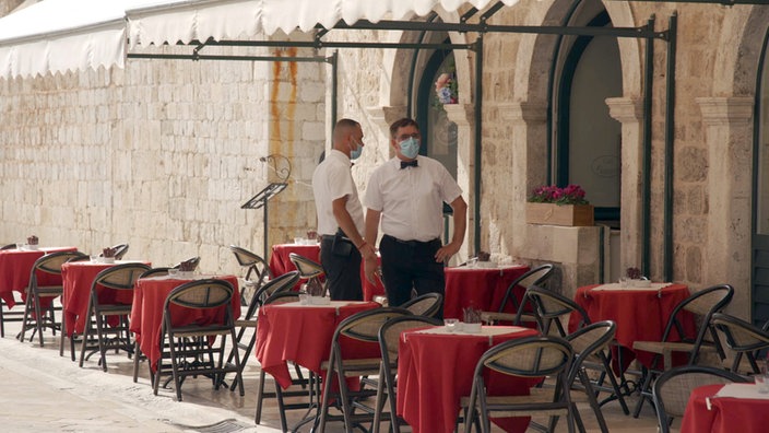 Dva konobara pripremaju stolove u restoranu