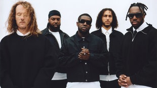 Das Londoner Ezra Collective mit schwarzen Jacken und weißen Hemden
