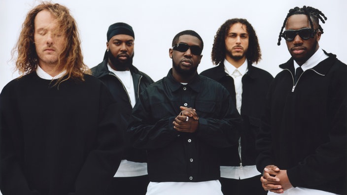 Das Londoner Ezra Collective mit schwarzen Jacken und weißen Hemden