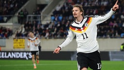 Nick Woltemade läuft mit ausgebreiteten Armen und einem erhobenen Zeigefinger im neuen DFB-Trikot über das Spielfeld (Nahaufnahme), im Hintergrund links läuft Florian Wirtz (unscharf), nach Woltemade-Tor bei der WM-Quali 14.11.2025