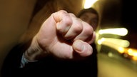  Ein junger Mann hebt seine geballte Faust 