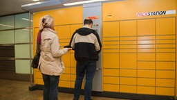 Mann und Frau stehen vor einer Packstation