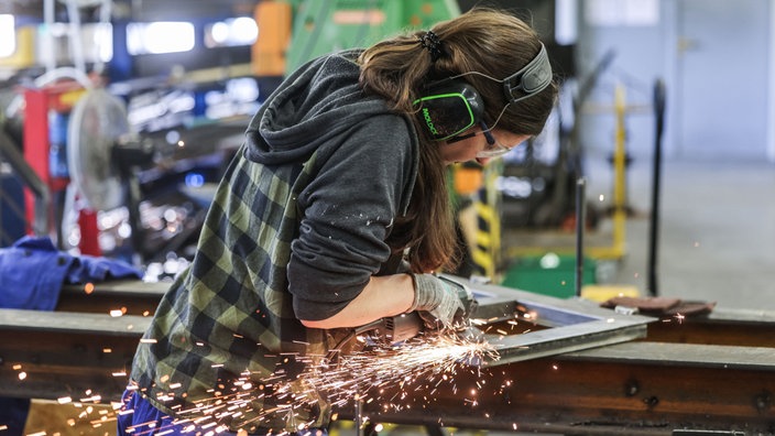 Eine Auszubildende zur Metallbauerin arbeitet im AusbildungsCampus Butzweilerhof in Köln mit einem Schleifgerät (Archivfoto vom 03.03.2026)