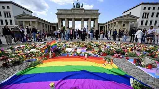 Am Brandenburger Tor in Berlin liegen rund um eine Regenbogenflagge Blumen und Kerzen nach dem tödlichen Anschlag beim CSD am 25.07.27 (Foto vom 27.07.2026)