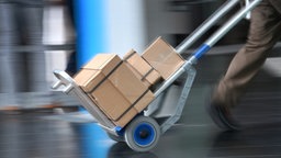 Paketzusteller mit zahlreichen Paketen auf einer Lastkarre
