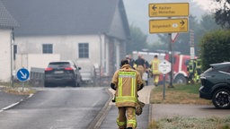 Ein Feuerwehrmann geht am 17.08.2026 eine Straße entlang