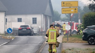 Ein Feuerwehrmann geht am 17.08.2026 eine Straße entlang
